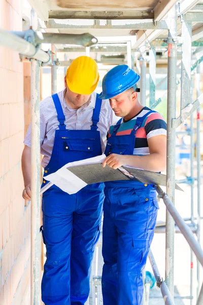 Construction Team with building plans on site — Stock Photo, Image