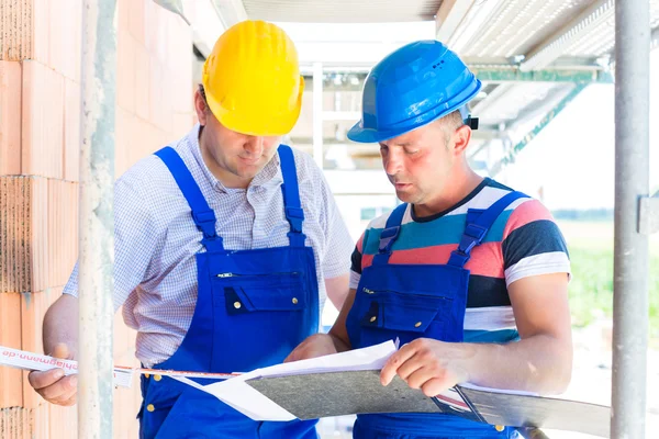 Construction Team with building plans on site — Stockfoto