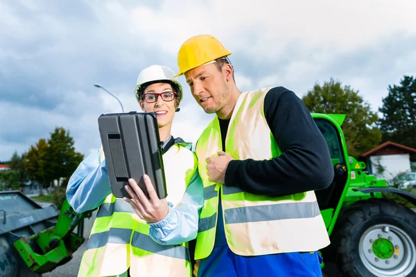 Builders with blueprint on construction site — Stockfoto