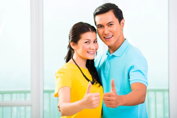 Giovane coppia asiatica in appartamento con i pollici in su — Foto Stock
