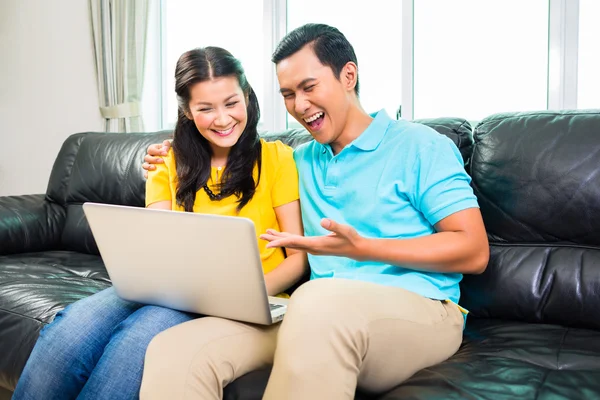 Aziatische paar met behulp van laptop op sofa — Stockfoto