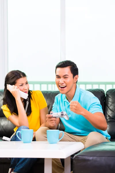 Paret spelar TV-spel och telefon — Stockfoto
