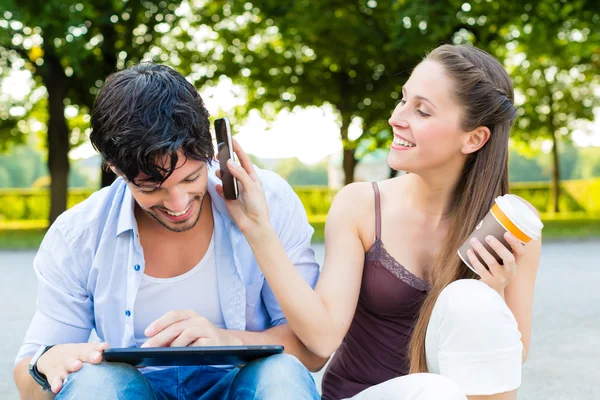 Par i stadsparken med tablet PC — Stockfoto