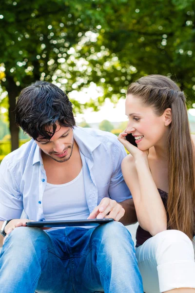Par i stadsparken med tablet PC — Stockfoto