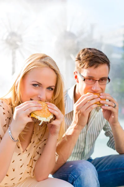 Pasangan lapar dan makan burger saat istirahat — Stok Foto