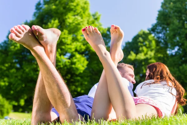Vrienden leggen met gekruiste benen in park — Stockfoto