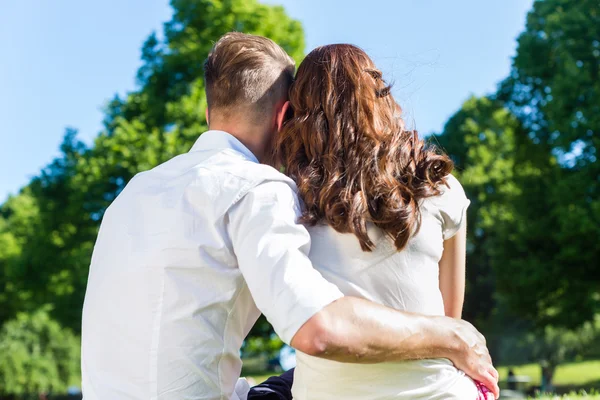 Casal apaixonado sentado no gramado do parque — Fotografia de Stock