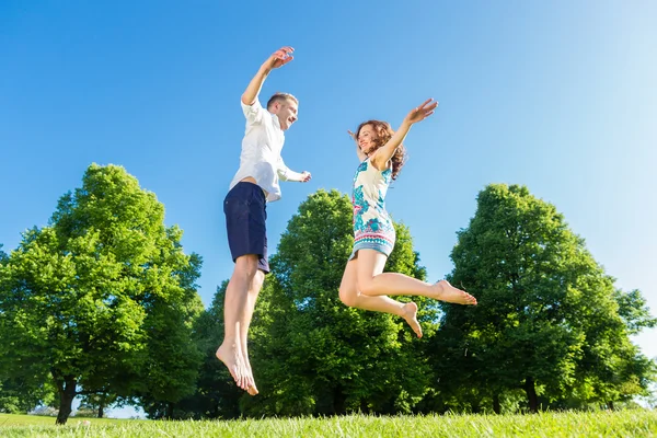 Casal apaixonado pulando no gramado do parque — Fotografia de Stock