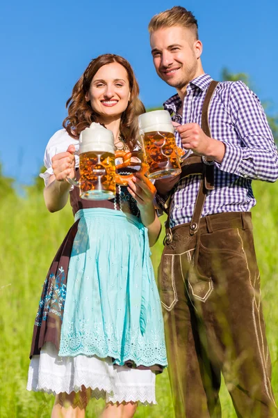 Casal alemão em Tracht com cerveja e pretzel — Fotografia de Stock