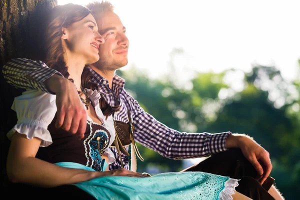 Casal bávaro em Tracht abraçando debaixo da árvore — Fotografia de Stock