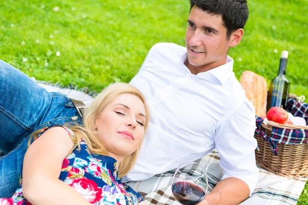 Pareja teniendo picnic ingenio vino en el prado — Foto de Stock