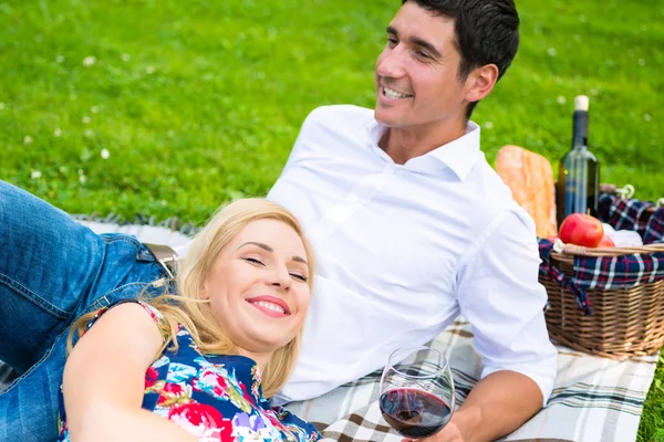 Casal fazendo piquenique com vinho no prado — Fotografia de Stock