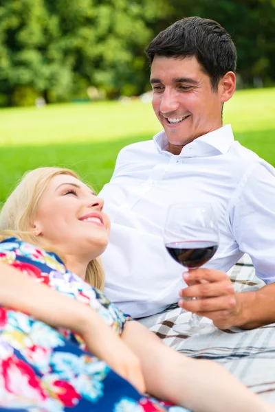 Пара пьющих вино на траве парка — стоковое фото