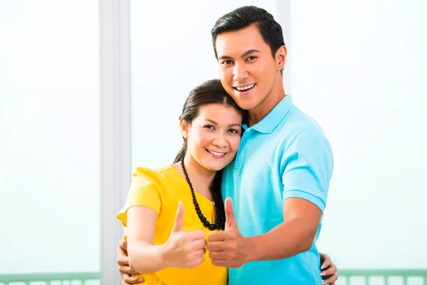 Asian couple in apartment with thumbs up Royalty Free Stock Images