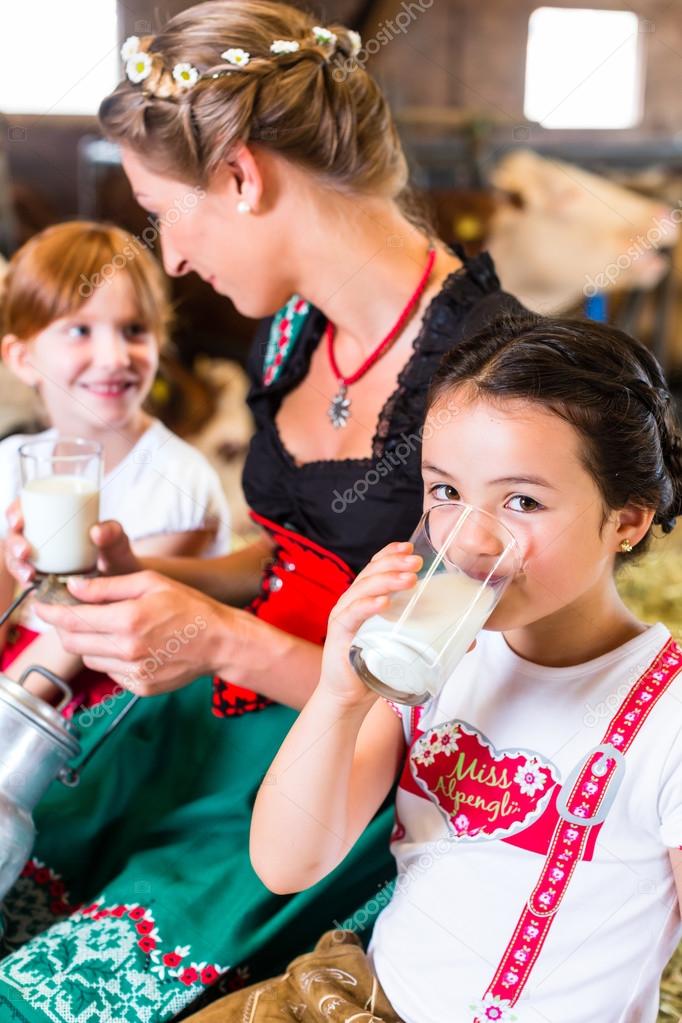 family drinking milk in cow barn