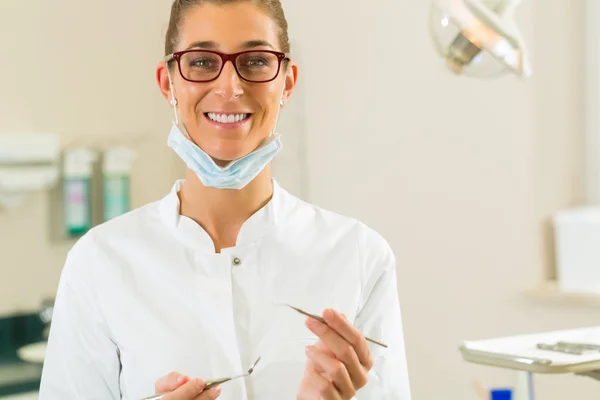 Dentiste dans sa chirurgie tenir miroir et grattoir — Photo