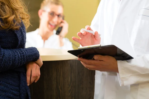 Vrouw en arts bij de receptie van kliniek — Stockfoto