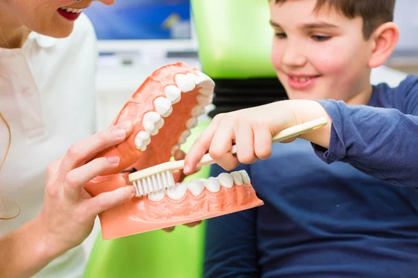 Dentiste expliquant le nettoyage des dents garçon — Photo