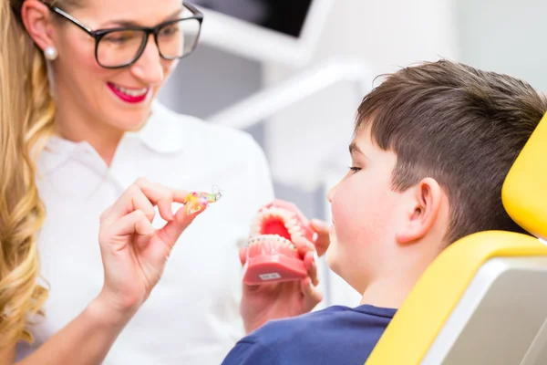 Kobiece ortodonta wyjaśniający chłopiec szelki — Zdjęcie stockowe