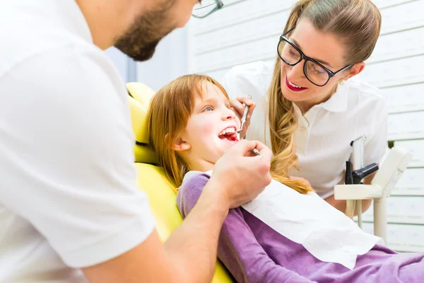 Dentista que da tratamiento a la niña en cirugía dental — Foto de Stock