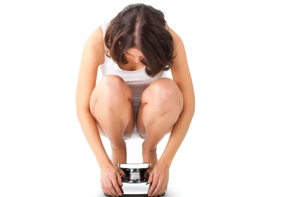 Woman sitting on her haunches on a scale — Stock Photo, Image