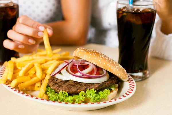 Wanita makan hamburger dan minum soda — Stok Foto