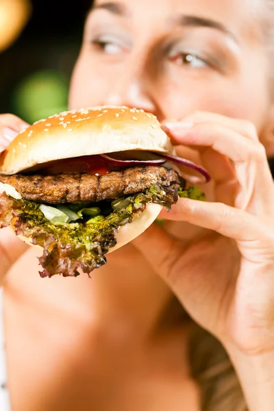 Frau im Restaurant isst Hamburger — Stockfoto