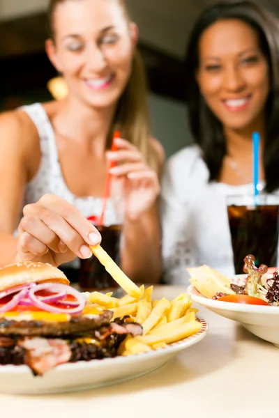 Женщины едят гамбургер и пьют газировку — стоковое фото