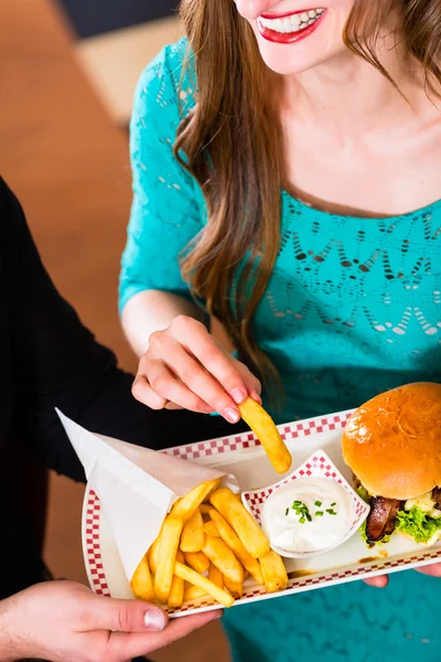 Pareja comiendo comida rápida con hamburguesas y papas fritas — Foto de Stock