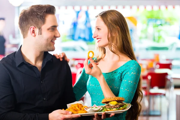 Pasangan makan makanan cepat saji dengan burger dan kentang goreng — Stok Foto