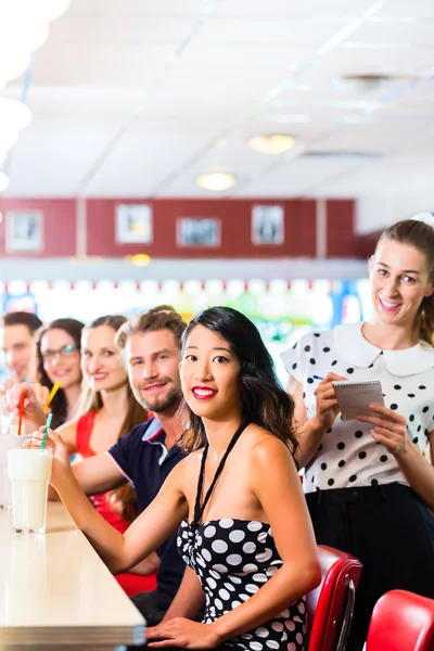 Människor i amerikansk diner med milkshakes — Stockfoto