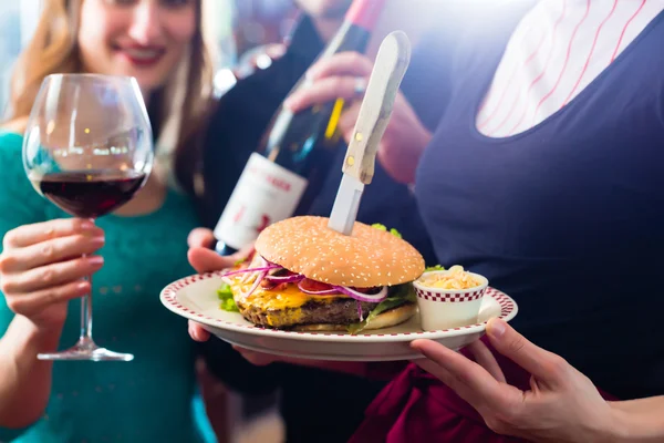 Pessoas no restaurante americano com hambúrguer e vinho — Fotografia de Stock