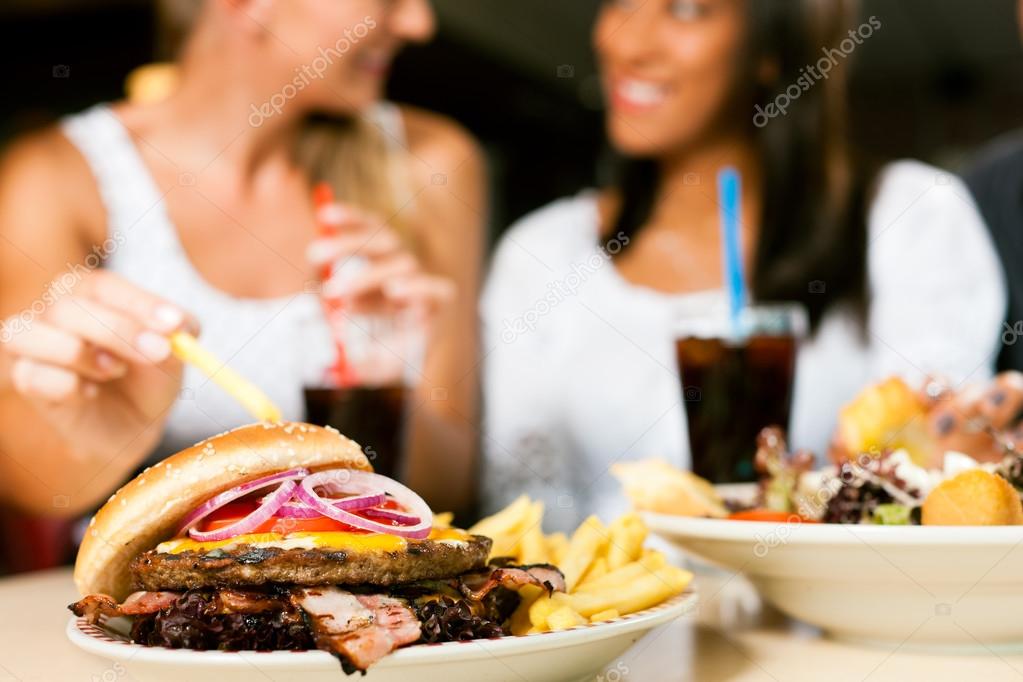 women eating hamburger and drinking soda