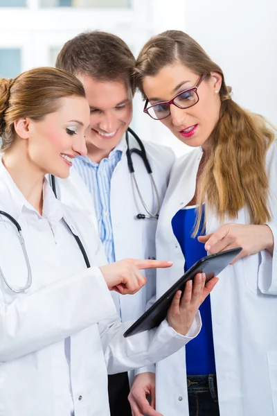 Equipe de médicos na clínica com computador tablet — Fotografia de Stock