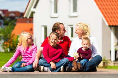 Mutlu bir aile evinin önünde oturuyor.