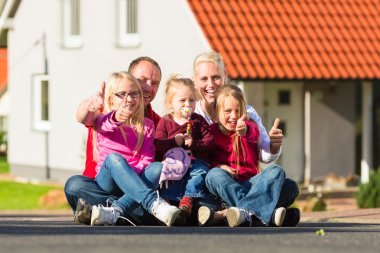 Mutlu bir aile evinin önünde oturuyor.