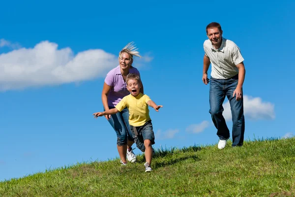 La famiglia all'aperto corre su un prato — Foto Stock