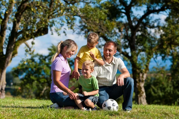 Famille avec enfants et football sur une prairie — Photo