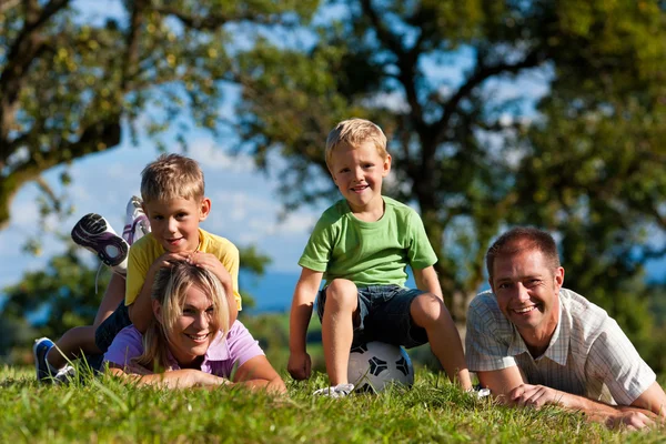 Famiglia con bambini e calcio su un prato — Foto Stock