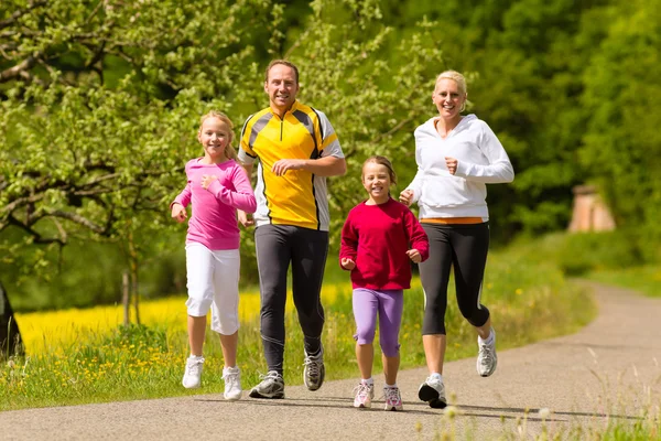 Famiglia in esecuzione nel prato per lo sport — Foto Stock