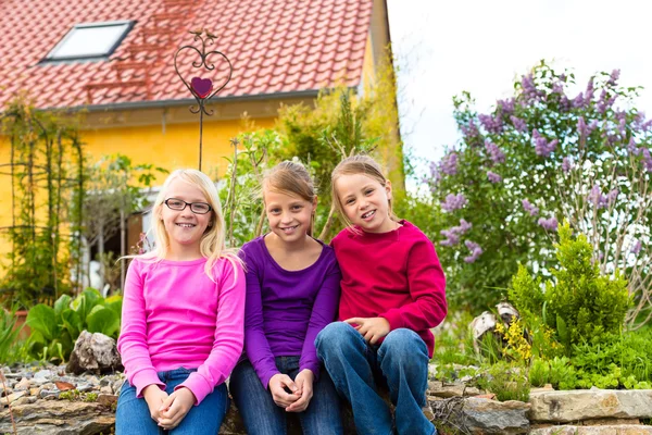 Skrattande barn sitta framför huset i trädgården — Stockfoto