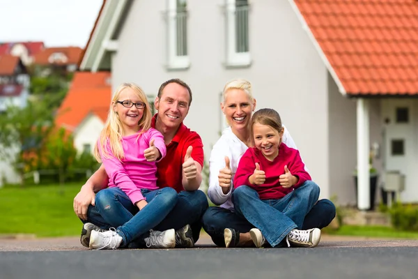 Familjen sitter framför hem — Stockfoto