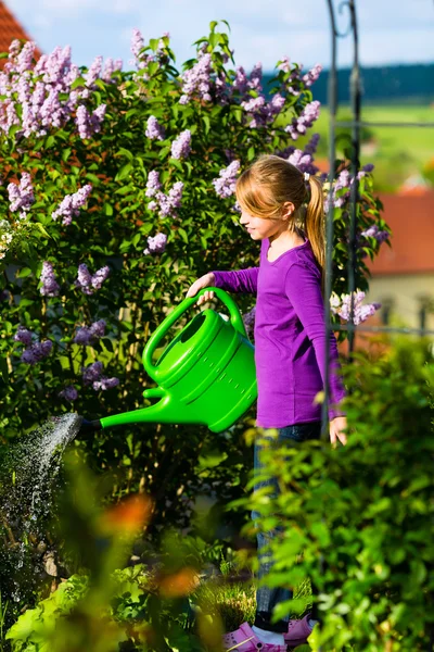 Happy child watering flowers in the garden — Stock Photo, Image
