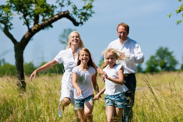 Família feliz correndo no prado — Fotografia de Stock