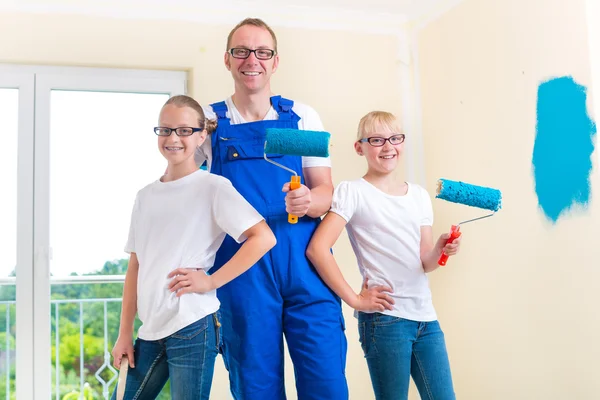 Pai e crianças pintam uma parede em casa — Fotografia de Stock