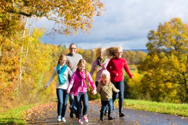 Family take a walk in autumn forest clipart
