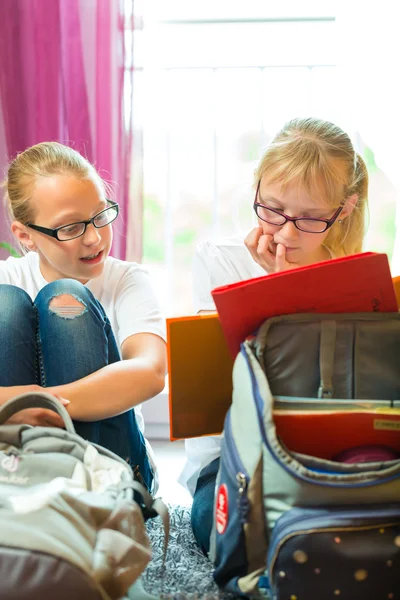 Mädchen machen Hausaufgaben und packen Schultüten — Stockfoto