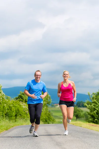 Couple heureux faisant du jogging sportif dans la rue rurale — Photo