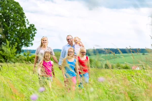 Familia feliz caminando en el prado — Foto de Stock