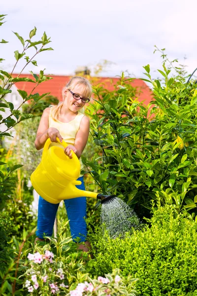 Joyeux enfant arrosant des fleurs dans le jardin — Photo